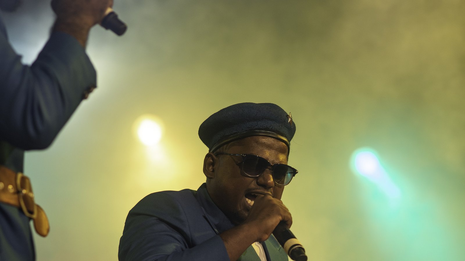 Rapper Arivu singing into a microphone on a smoky stage while performing with The Casteless Collective