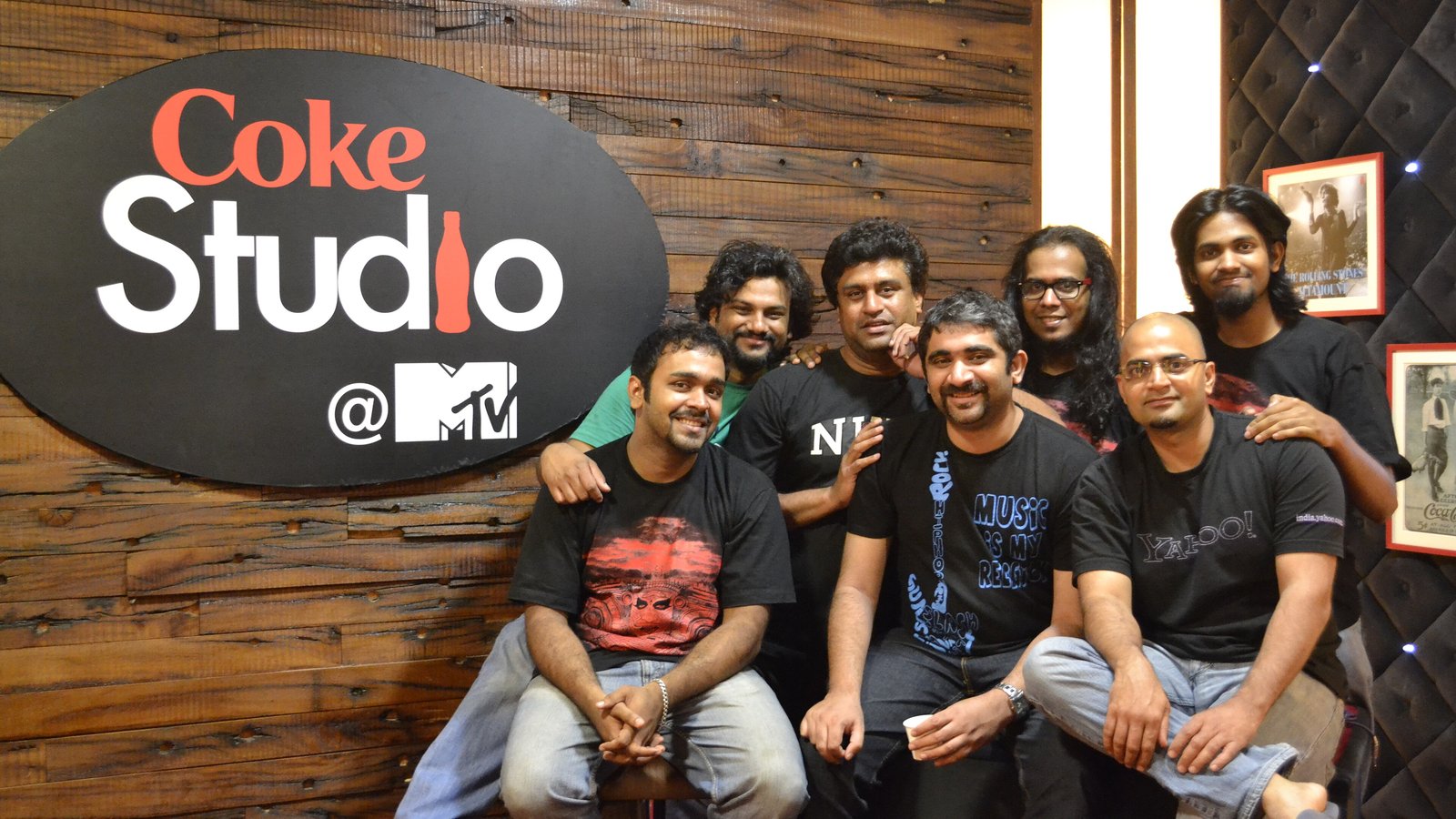 Seven members of Bengaluru Carnatic progressive rock band Agam posing together beside a Coke Studio @ MTV sign in 2012