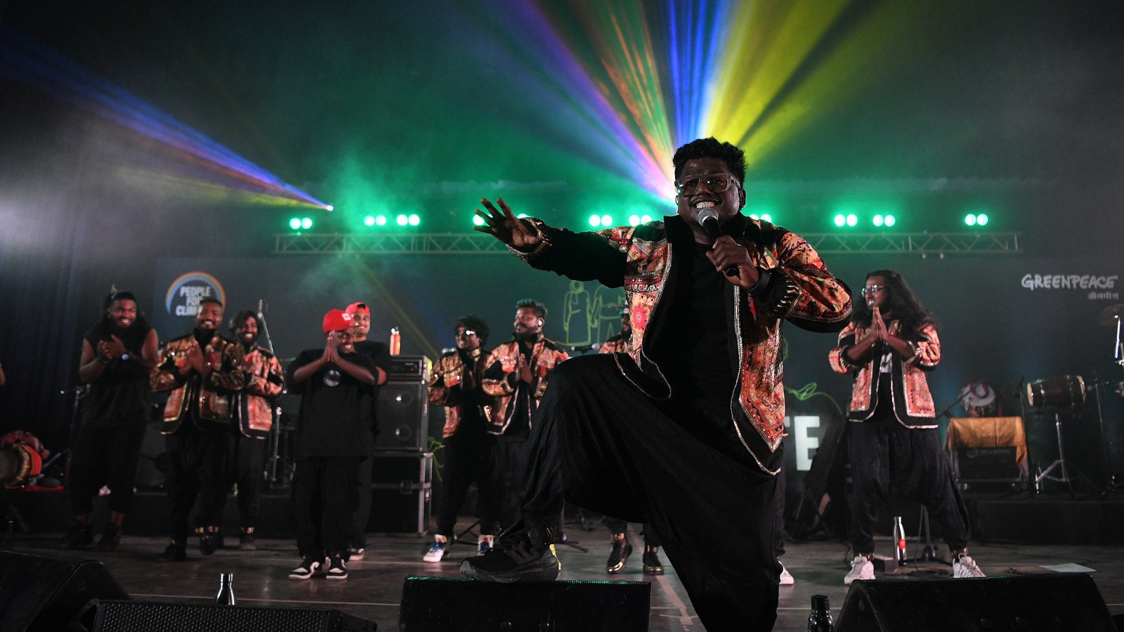 Tamil rapper Arivu performing on stage with a microphone at a Greenpeace event in 2024