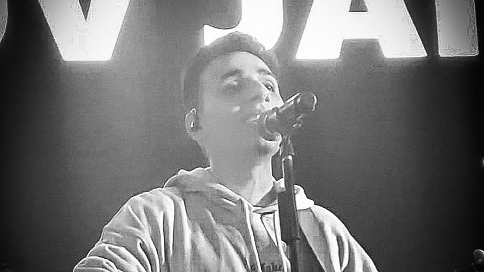 Black-and-white photo of Anuv Jain singing into a microphone on stage with an acoustic guitar, Chandigarh, October 2021