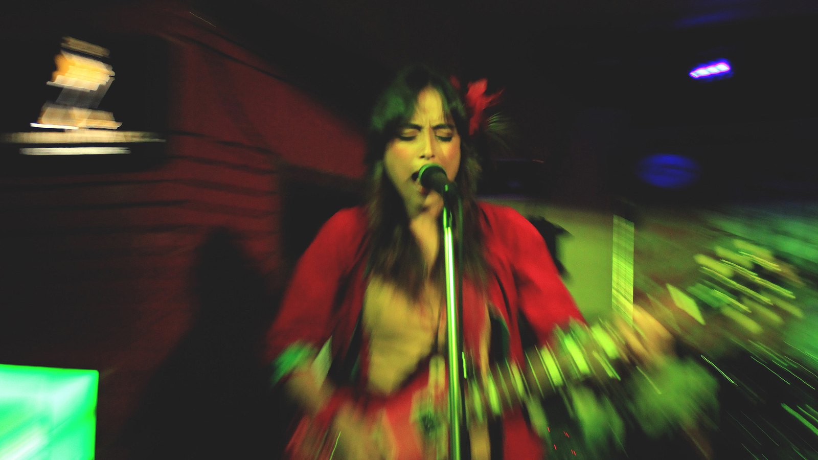 Tipriti Kharbangar of Shillong blues band Soulmate singing into a microphone in a red dress under green and red stage lights