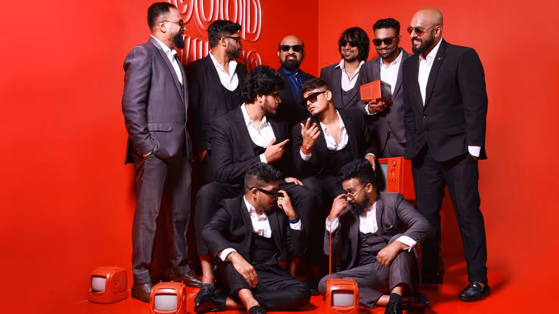 Masala Coffee band members in dark suits posing on a red set during a band photoshoot