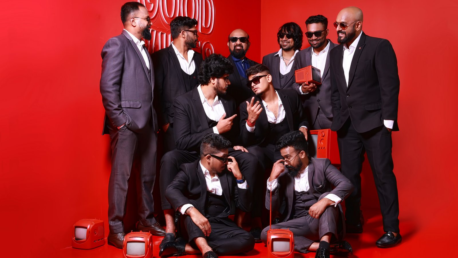 Masala Coffee band members in dark suits posing on a red set during a band photoshoot