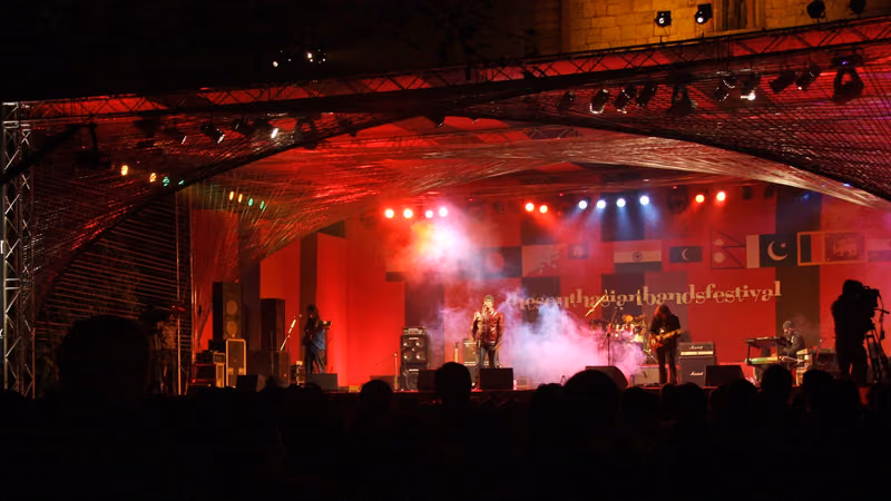 Indus Creed performing live on a red-lit stage at the South Asian Bands Festival at Purana Qila, New Delhi, in December 2010